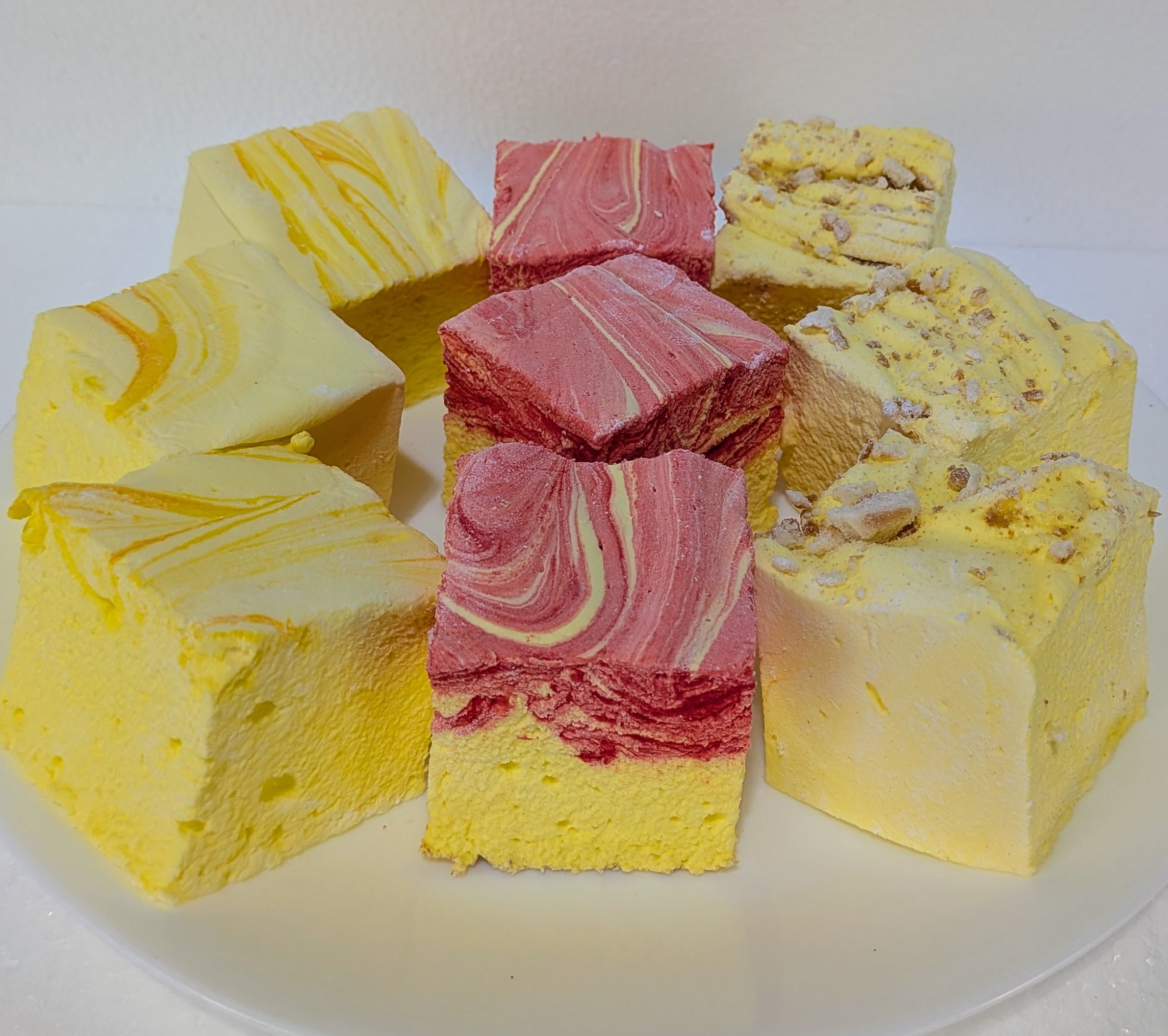 Yellow and pink swirled gourmet marshmallows pieces on a white plate