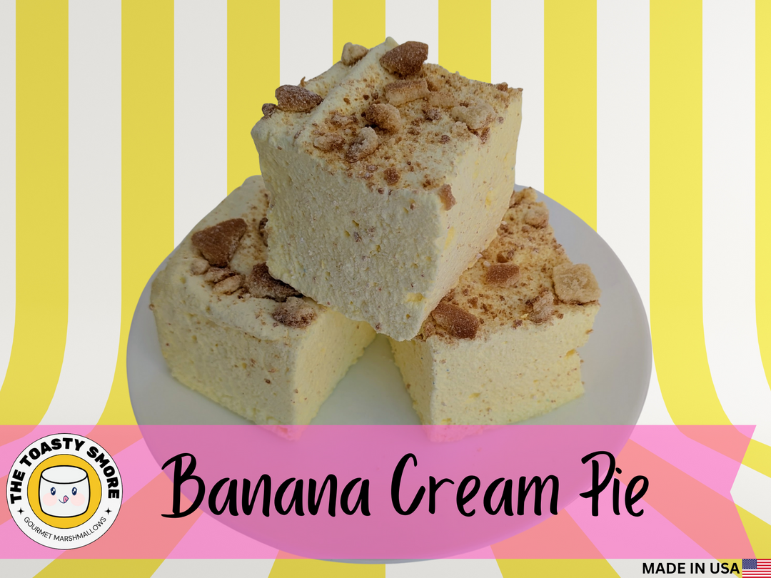 Three pieces of Banana Cream Pie gourmet marshmallows made with organic marshmallow root and premium beef gelatin, displayed on a plate with a colorful striped background and The Toasty S’more logo.