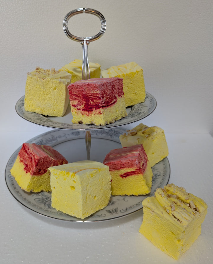 Three-tiered silver cake stand with yellow and red layered gourmet marshmallows on a white background