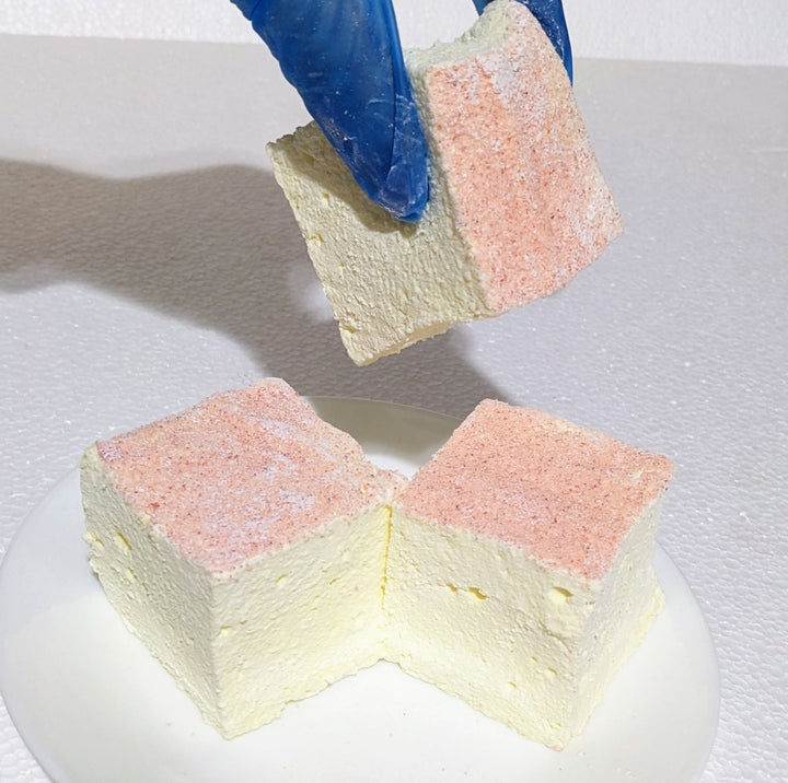 Handcrafted pink lemonade marshmallows, gently marbled with pink and yellow, arranged on a white plate for a visually striking, artisan presentation.
