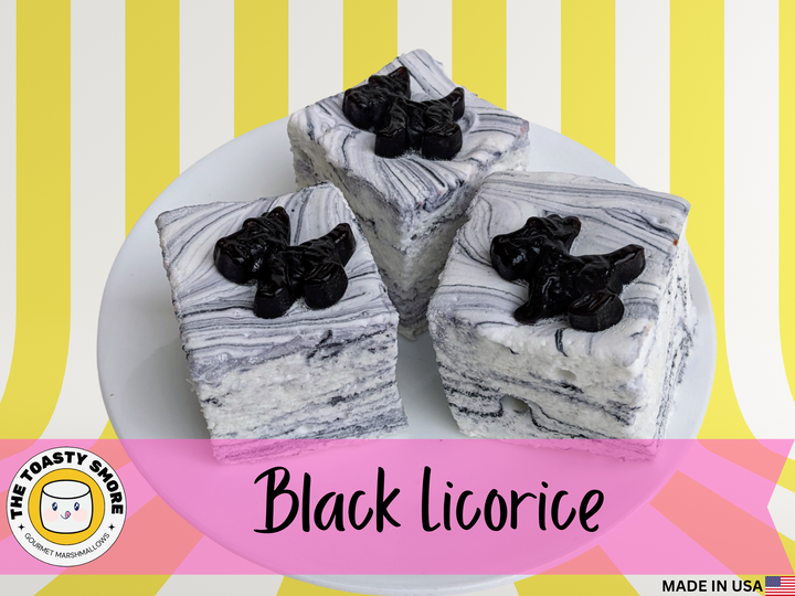 Three black licorice marshmallows, white with black swirls and streaks, displayed on a yellow and white striped background. The image features The Toasty Smore logo and a "Made in USA" flag