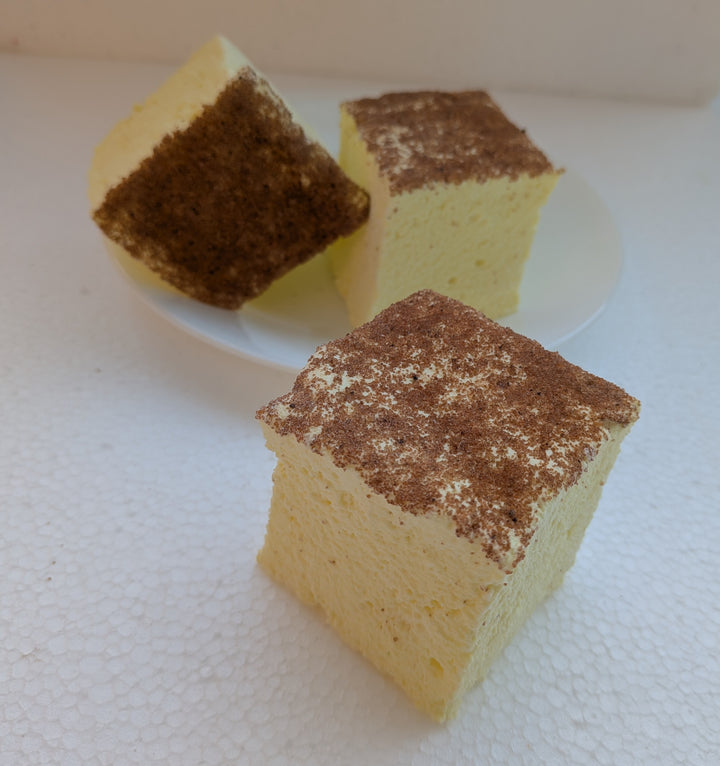 Three pieces of creme brulee gourmet marshmallow with a brown crumb topping on a white surface.