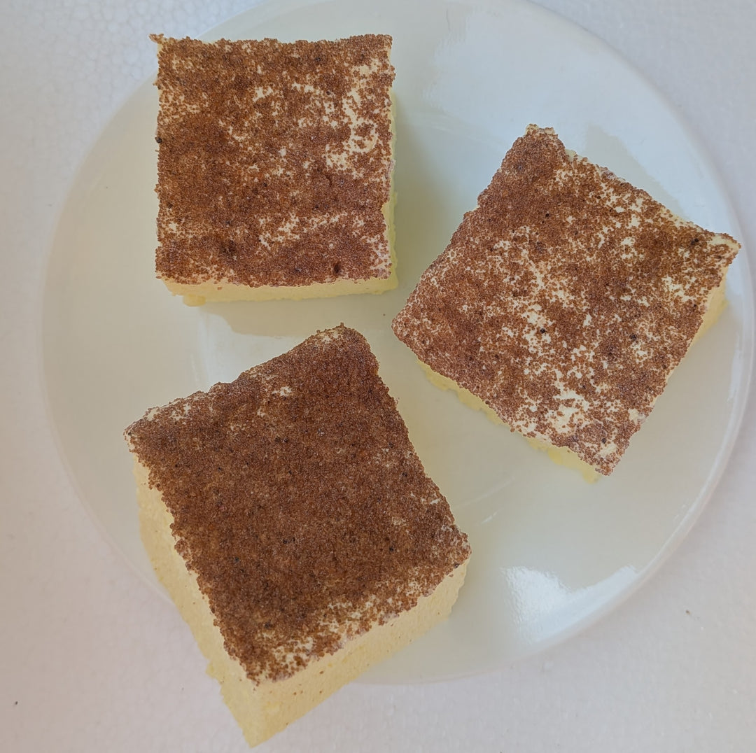Three square pieces of creme brulee gourmet marshmallow with caramel sugar topping on a white plate.