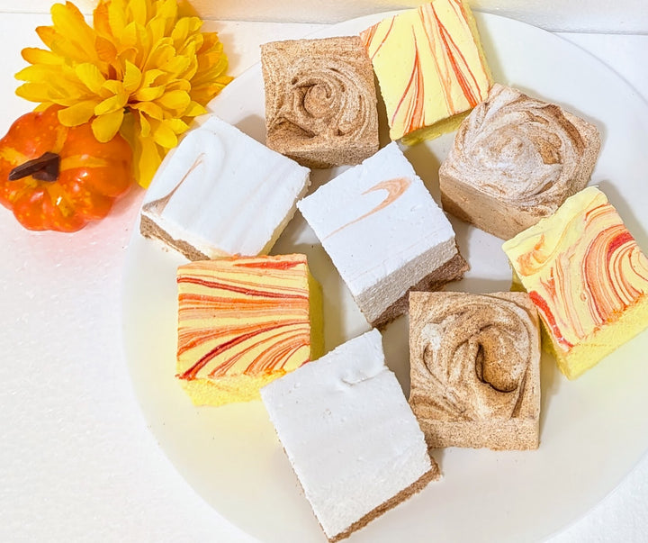 Assorted fall cravings gourmet marshmallow bundle with autumnal colors on a white surface with decorative elements.