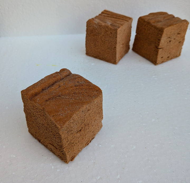 Three pumpkin spice marshmallows on a white surface