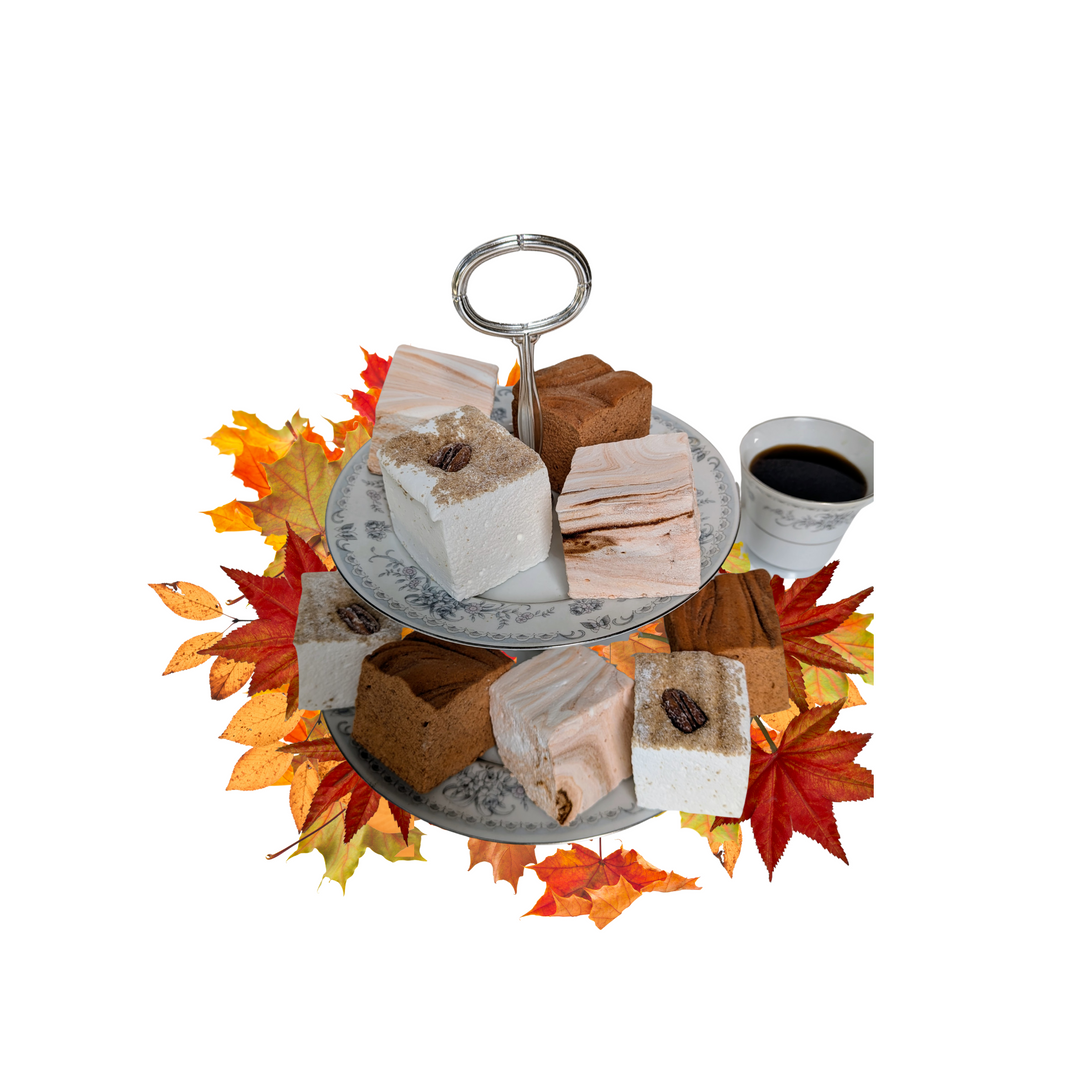 Assorted gourmet marshmallows for autumn on a stand with a cup of coffee and autumn leaves on a white background
