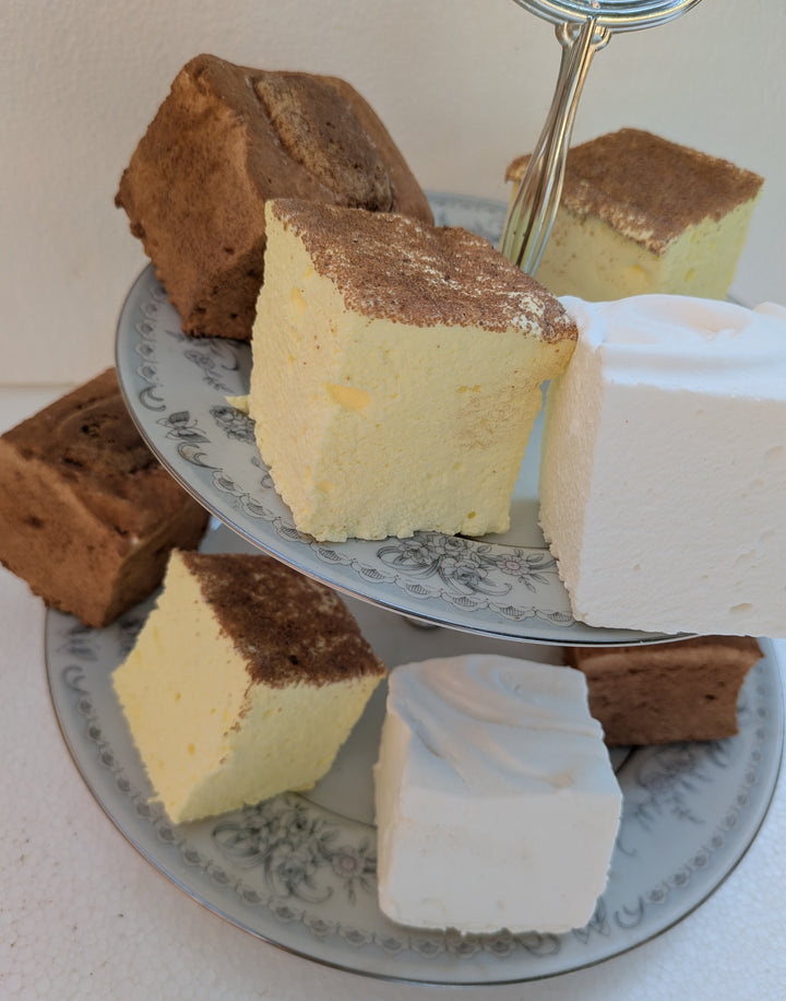 Three-tiered cake stand with slices of different types of gourmet marshmallows on a white surface.