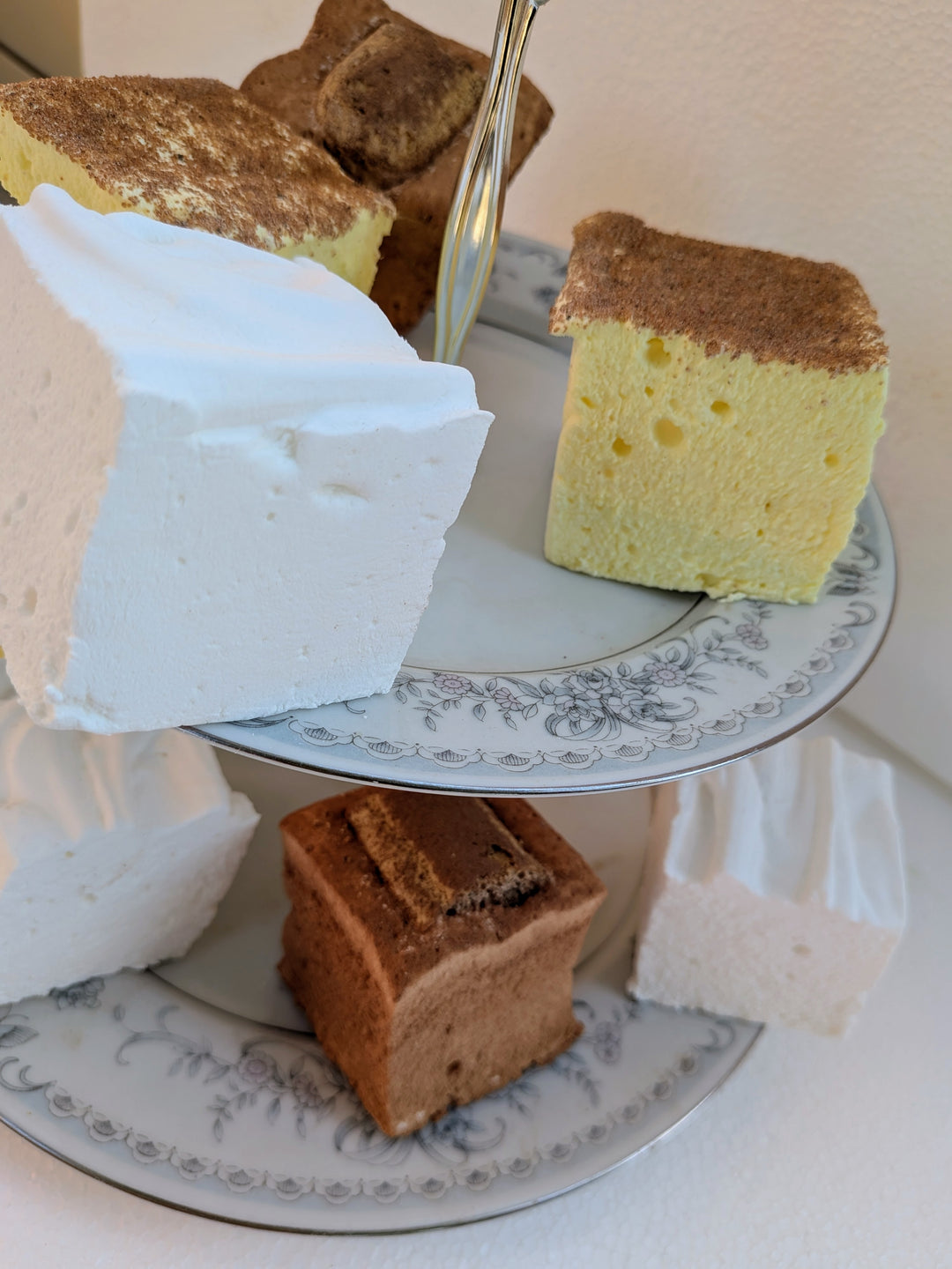 Three slices of gourmet marshmallows on a decorative plate with a white napkin.