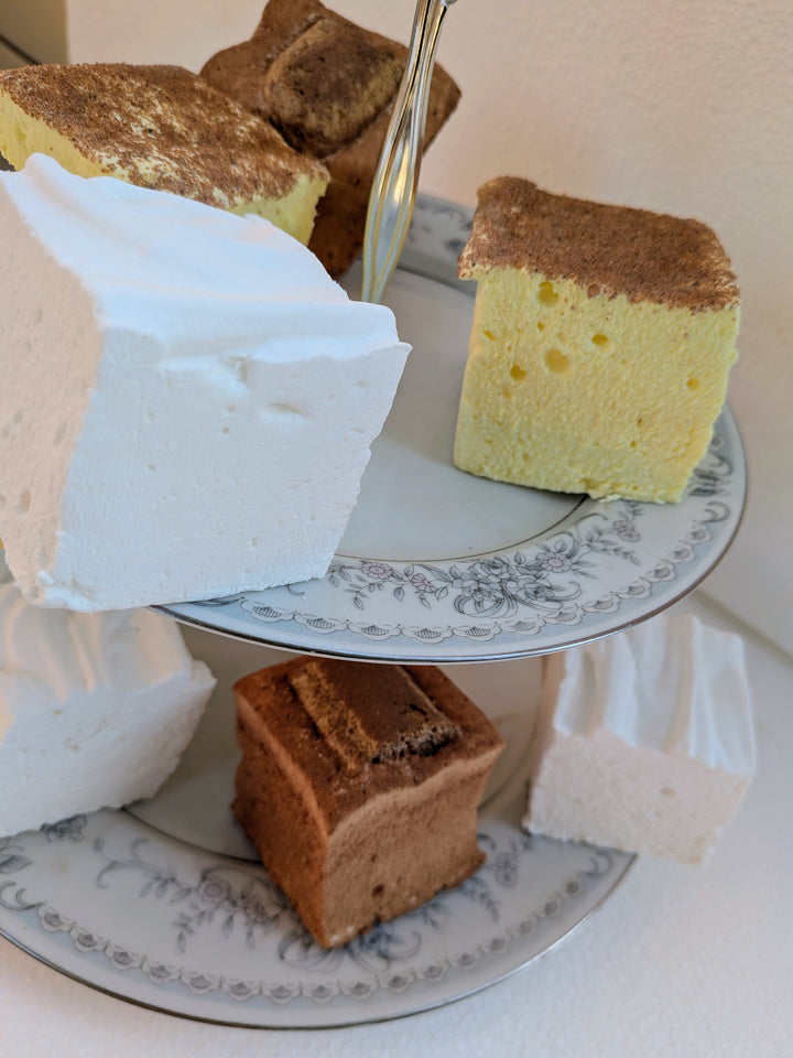 Three slices of gourmet marshmallows on a decorative plate with a white napkin.