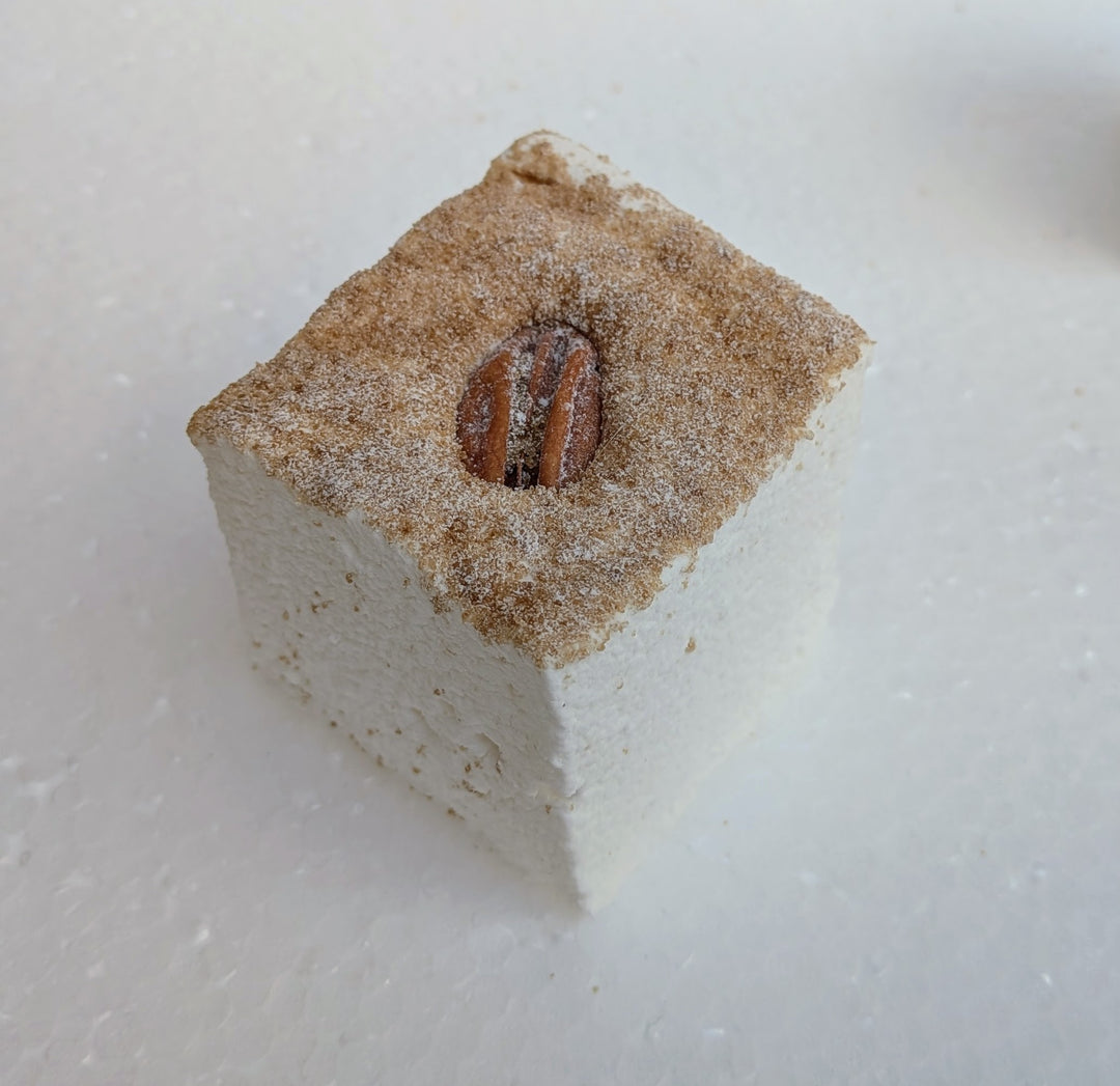 maple pecan pie gourmet marshmallows with a pecan on top, dusted with brown sugar, on a white surface.