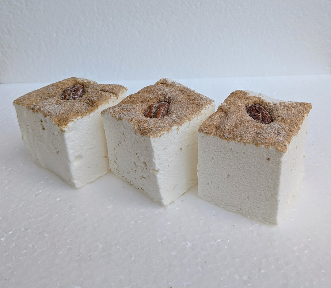 Three maple pecan pie gourmet marshmallows with pecans on top on a white background