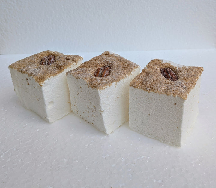 Three maple pecan pie gourmet marshmallows with pecans on top on a white background