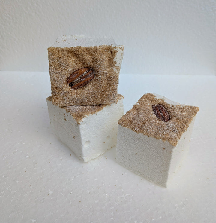 Three square pieces of maple pecan pie gourmet marshmallows with pecans on a white background