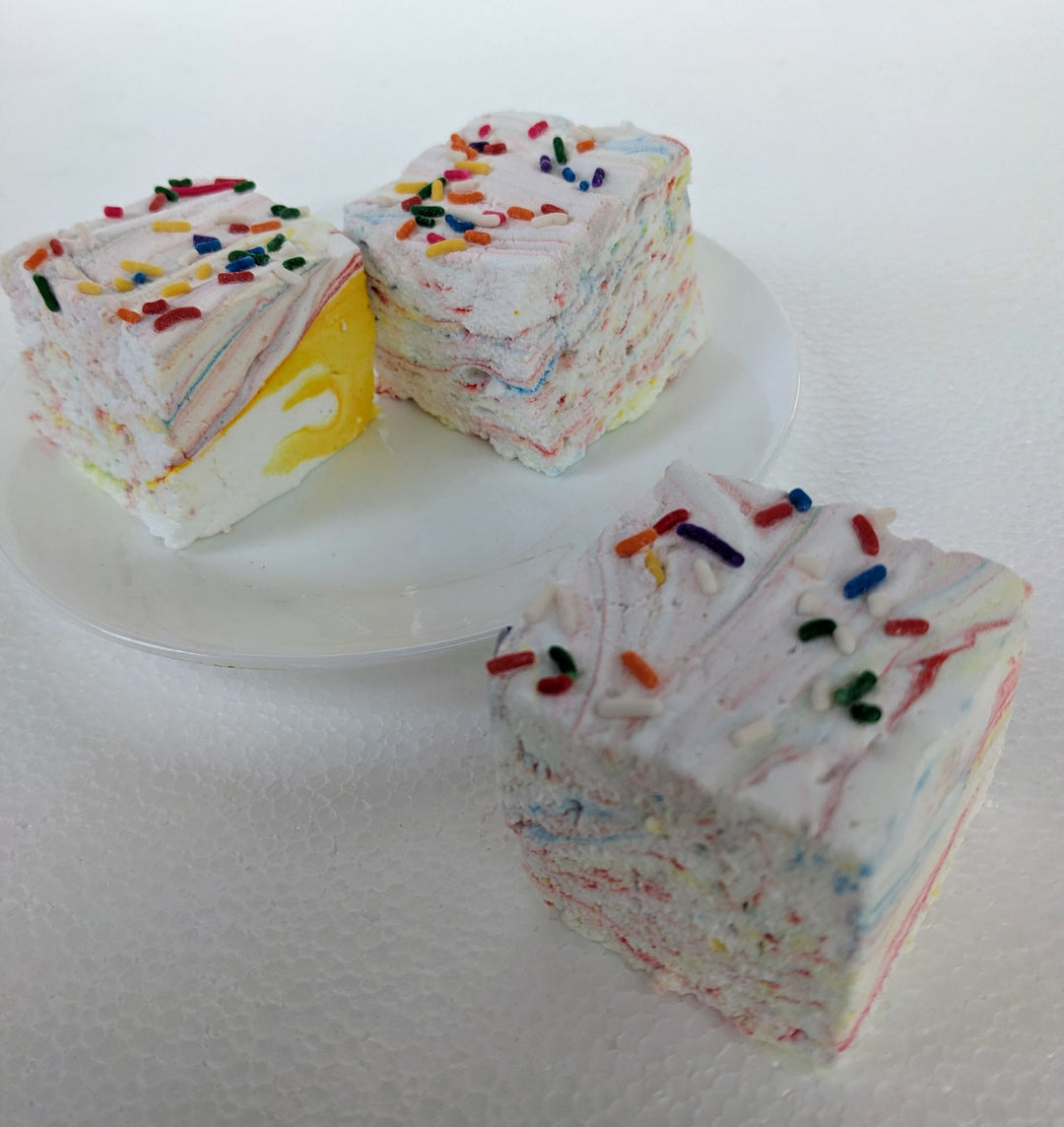 close view  of Three vibrant Tutti Frutti gourmet marshmallows with colorful swirls of fruity flavors, each topped with Rainbow sprinkles. Set against a clean white background, the marshmallows' soft, pillowy texture contrasts with the candy-coated crunch, creating a visually appealing and playful treat.