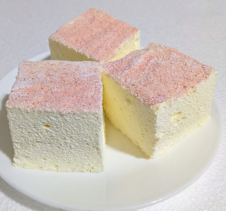 Handcrafted pink lemonade marshmallows, gently marbled with pink and yellow, arranged on a white plate for a visually striking, artisan presentation.