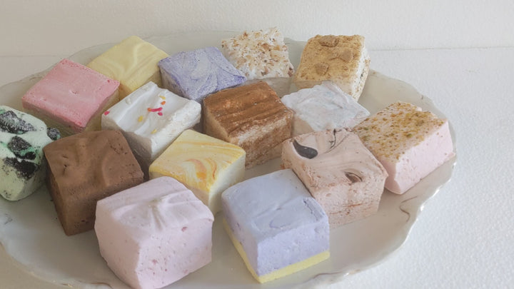 video showing a plate of a Variety of Gourmet Marshmallows in Assorted Colors and Flavors Spread Out on a White Plate with a White Background