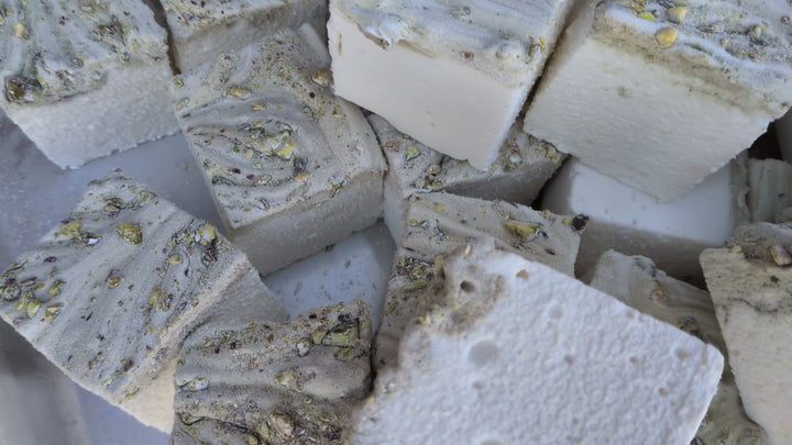 Pile of pistachio marshmallows made with beef gelatin and organic marshmallow root, showing a white base with a swirled pistachio‑studded top. Clean‑label, corn syrup‑free, gluten‑free real marshmallows photographed in a close‑up food shot.