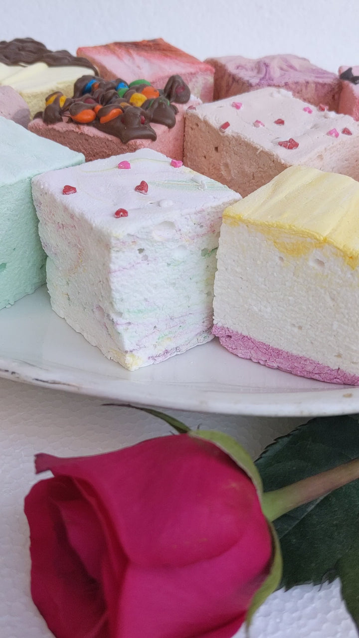 A plate of gourmet marshmallows, including flavors creme brulee, peanut butter, salted caramel, butter vanilla, mint, tutti frutti, banana split, toasted strawberry cheesecake, dulce de leche, wild cherry chip, amaretto, and double Dutch chocolate.