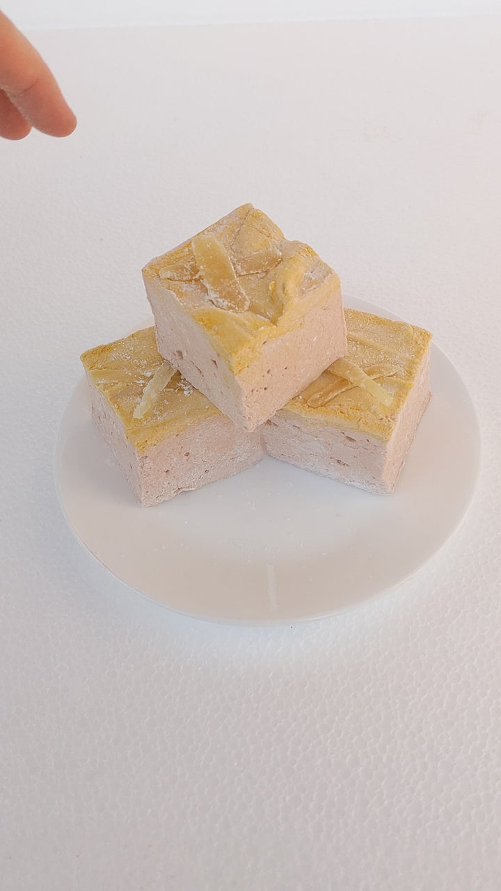 Hand Picking Up Handcrafted Gingerbread Marshmallow for Squeeze Test – Trio on White Plate