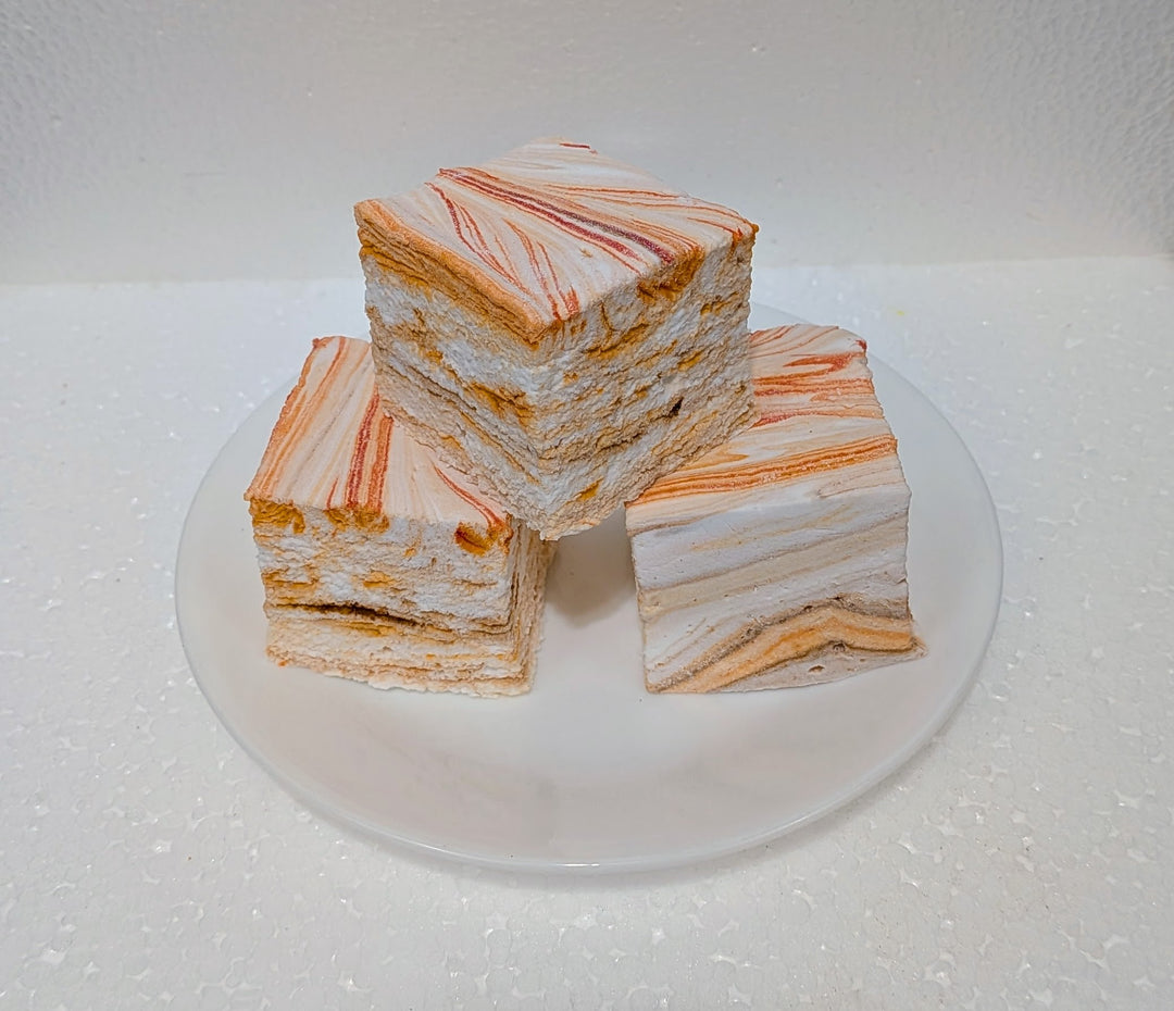 Three layered pumpkin chai gourmet marshmallows on a white plate with a white background