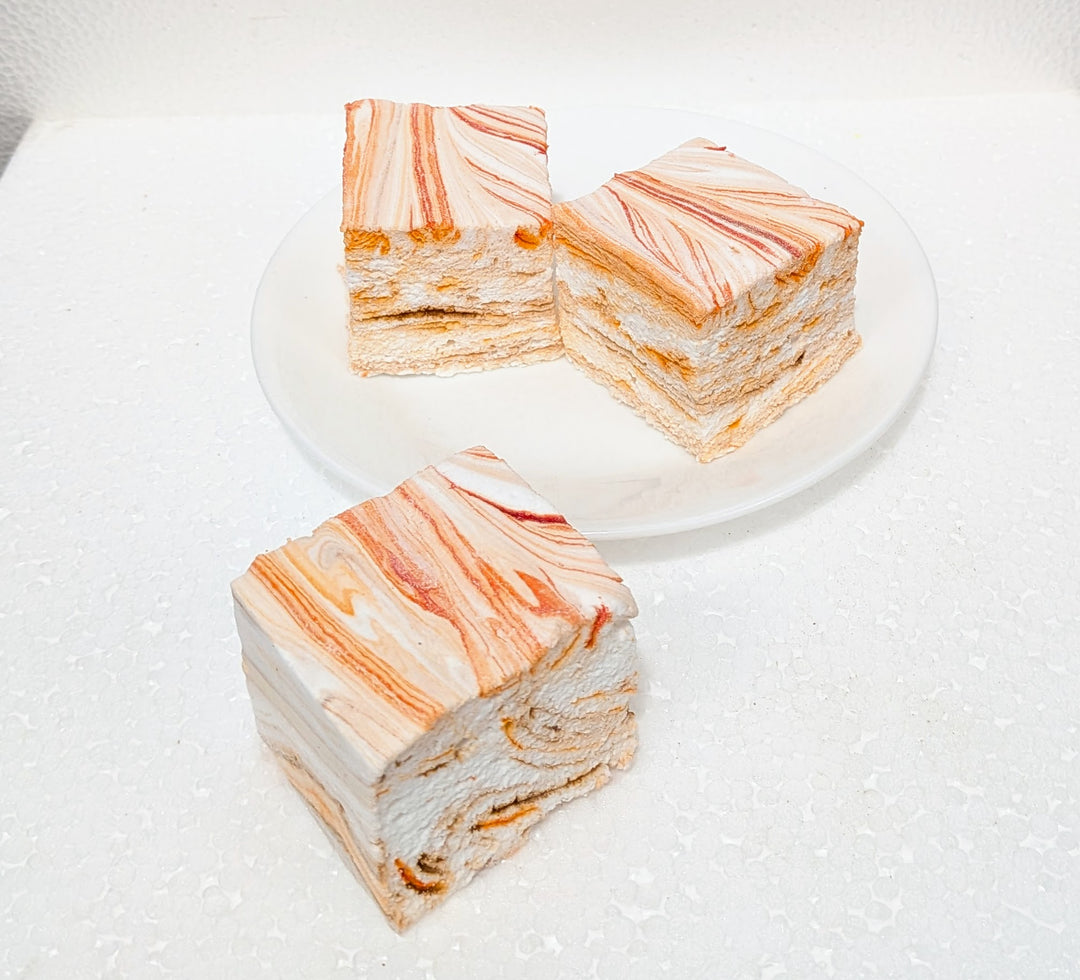 Three slices of pumpkin chai gourmet marshmallows with orange and white marbled pattern on a white plate.