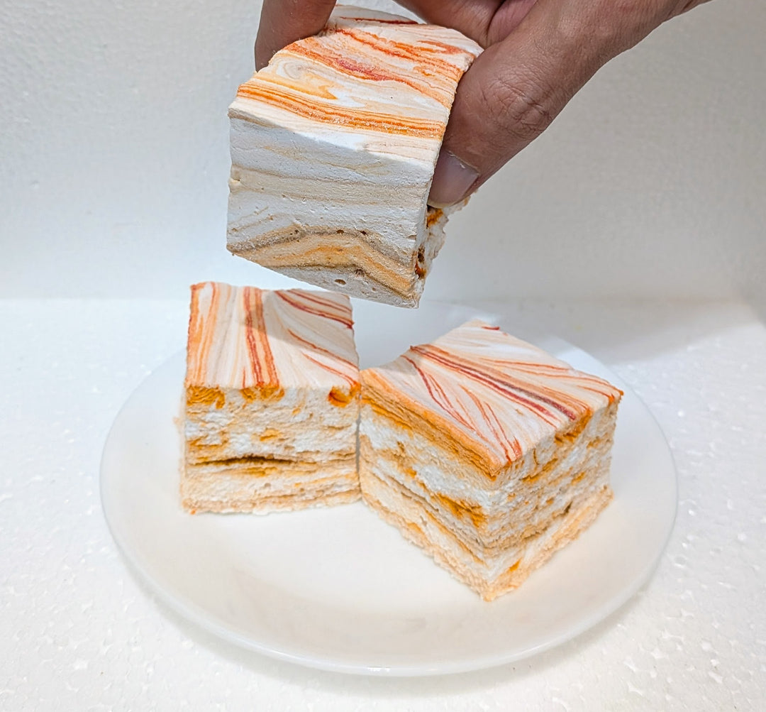pumpkin chai gourmet marshmallows with orange and white stripes on a white plate.