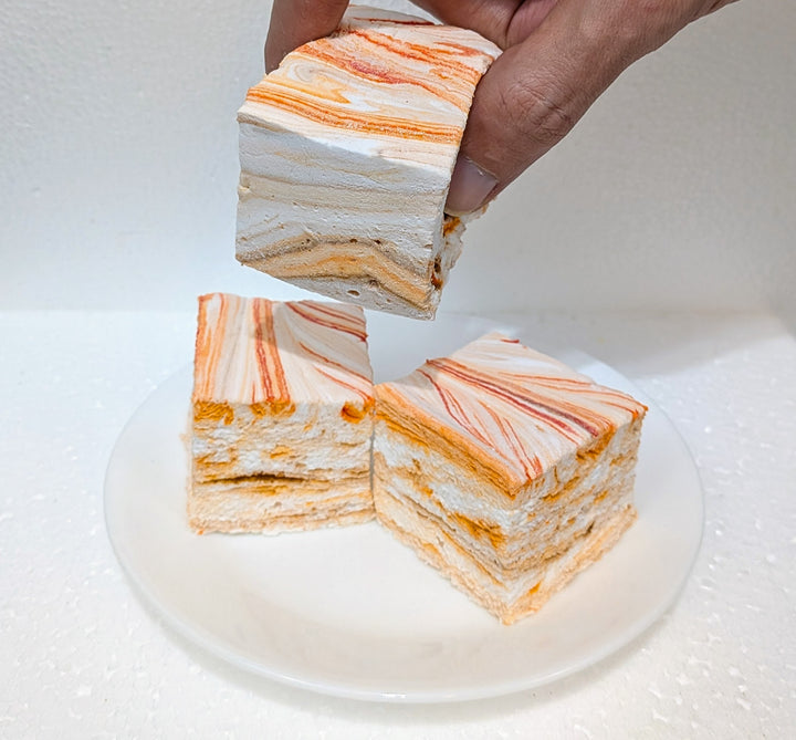 pumpkin chai gourmet marshmallows with orange and white stripes on a white plate.