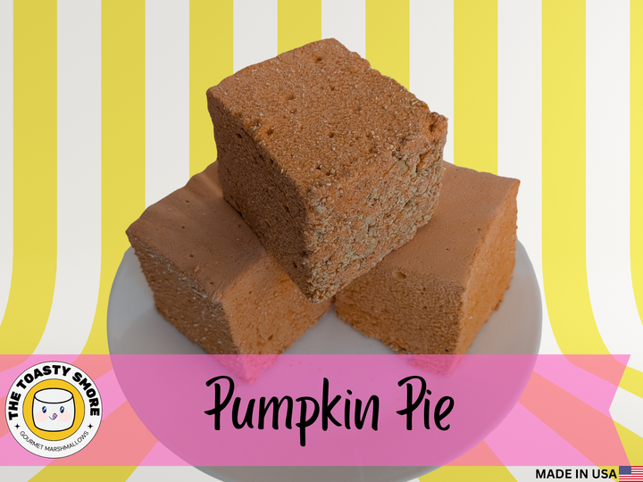 Three handcrafted Pumpkin Pie marshmallows stacked on a white background. Each 2-inch cube is a vibrant orange color with a smooth, airy texture and topped with a thin layer of golden graham cracker crust. The marshmallows are arranged in a pyramid, showcasing their bold fall-inspired hue and crisp crust detail.