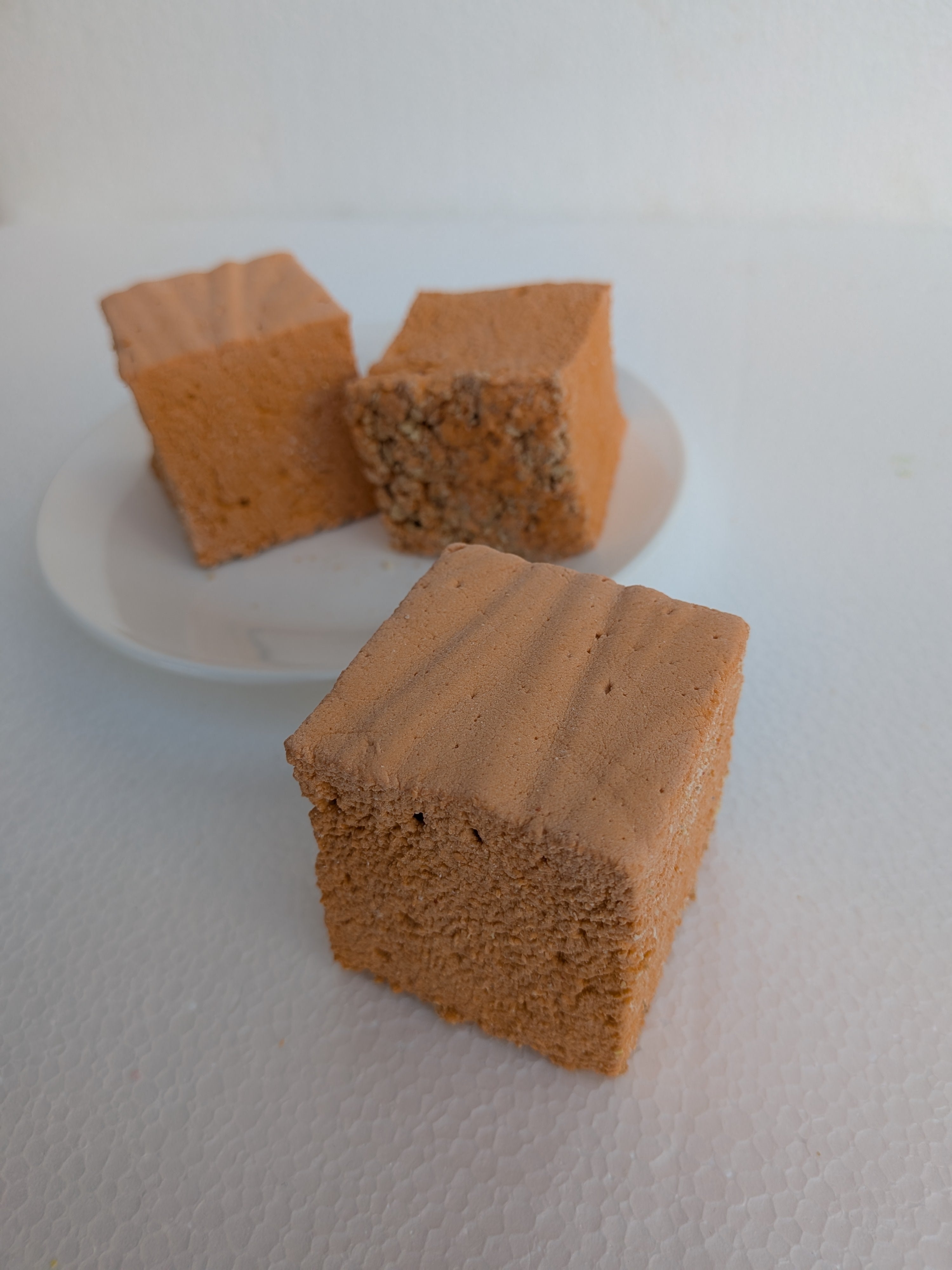Three square brown blocks on a white plate with a white background