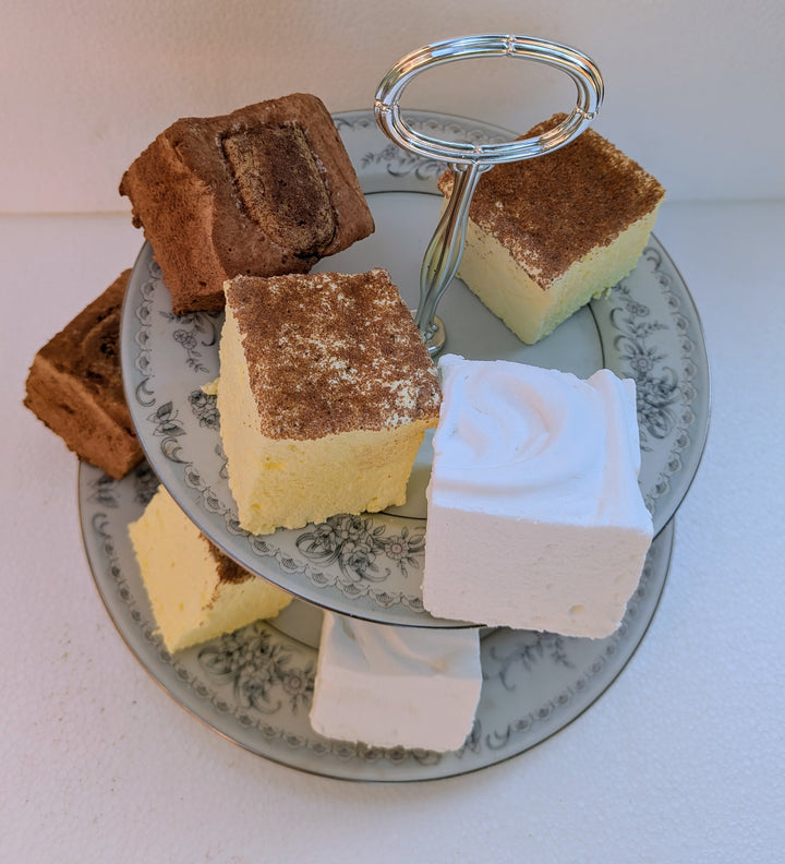 Three-tiered cake stand with various types of gourmet marshmallows slices on a white surface