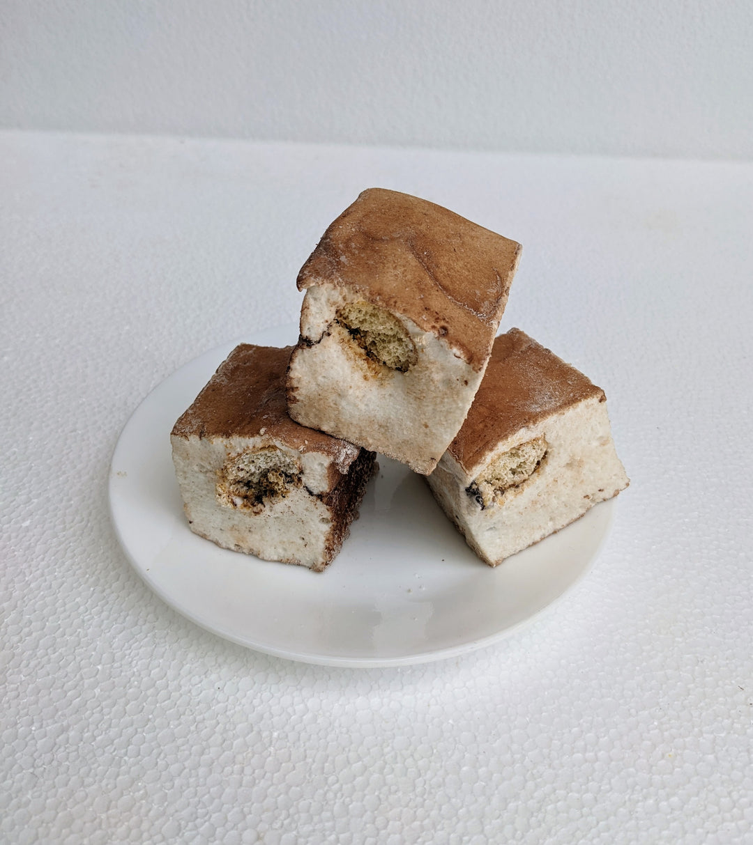 Three handcrafted tiramisu gourmet marshmallows, elegantly arranged on a plate, with a delicate dusting of cocoa powder. These fluffy, espresso-infused treats capture the essence of Italian dessert perfection, blending rich coffee notes with creamy mascarpone for a luxurious indulgence.