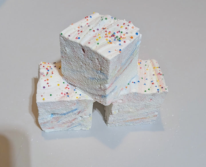Three jumbo Tutti Frutti marshmallows topped with rainbow sprinkles, displayed on a clean white background. Handcrafted by The Toasty S’more with organic marshmallow root, beef gelatin, and no corn syrup, these colorful 2-inch cubes offer a fruity, gluten-free treat perfect for gifting or snacking.
