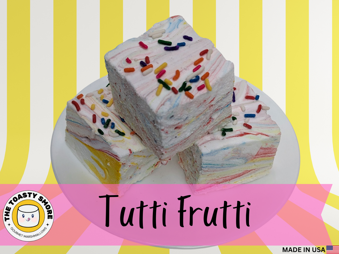 A trio of Tutti Frutti gourmet marshmallows with colorful swirls of fruity flavors, topped with Rainbow sprinkles. The bright, handcrafted marshmallows sit against a clean white background, highlighting their playful, candy-coated texture and pillowy softness.